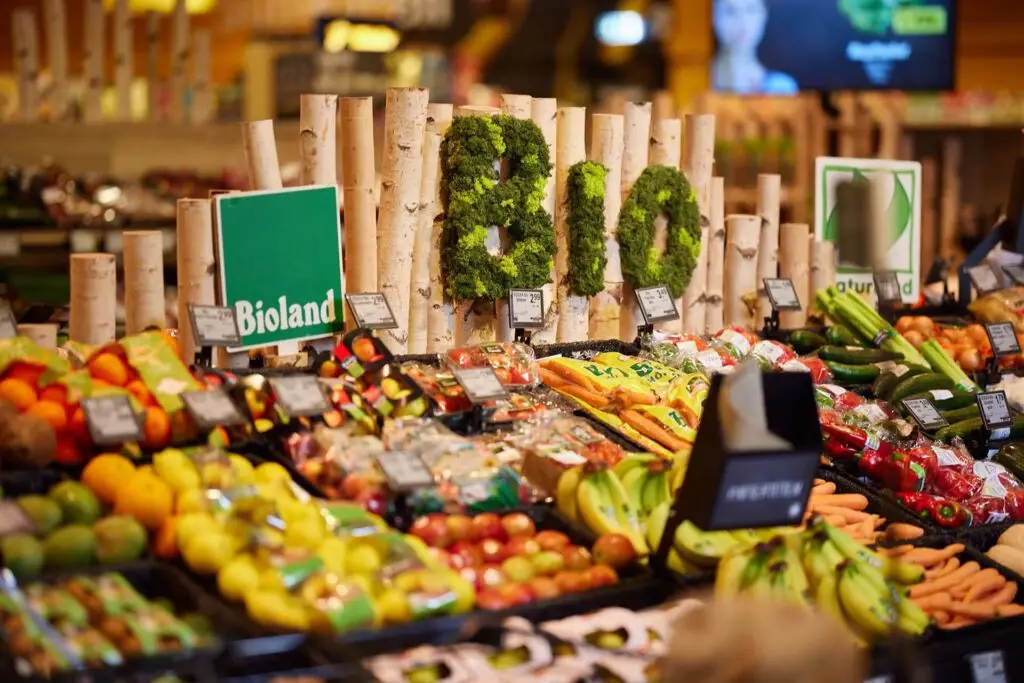 Bio-Obst und -Gem&uuml;se im Supermarkt: Bioland-Schild, moosige BIO-Dekoration und frisches Sortiment